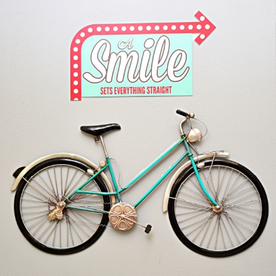 Bicycle hanging on the wall next to a smile sign